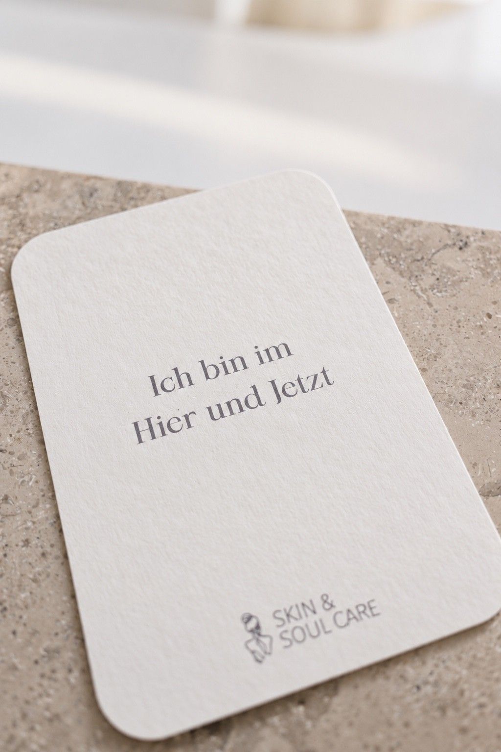 Karte mit dem Satz „Ich bin im Hier und Jetzt“ und dem Logo auf einem Tresen aus Naturstein