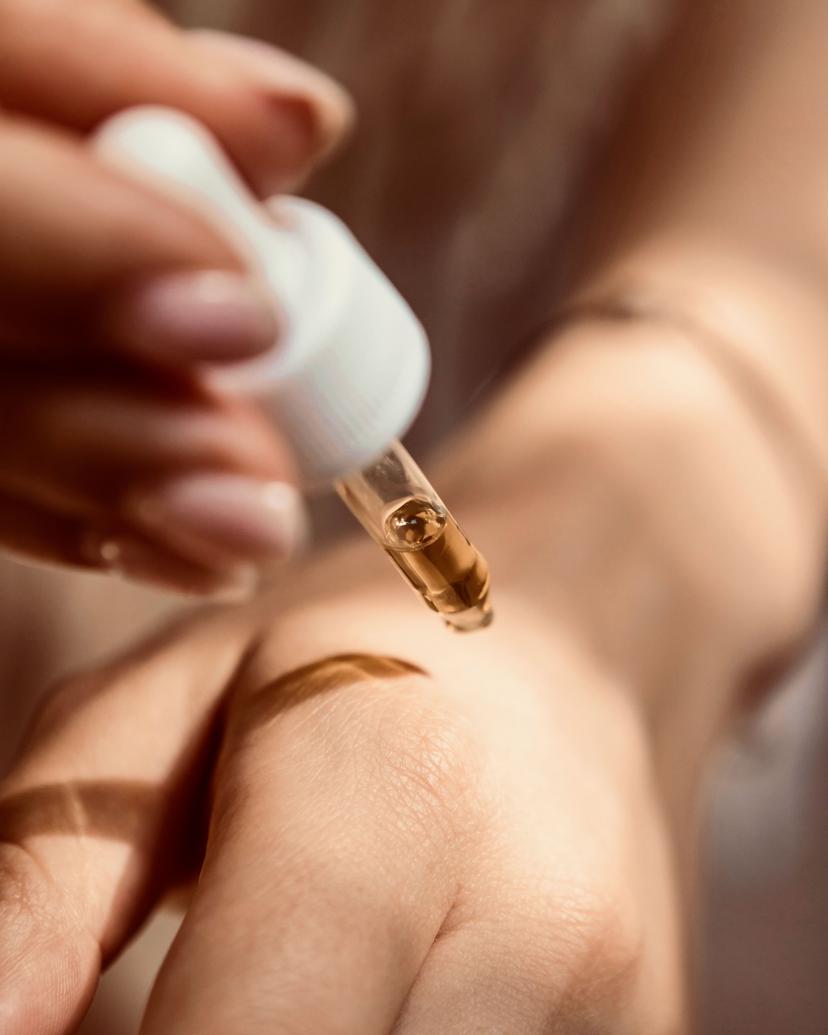 Frau trägt sich ein Pflegeprodukt mit einer Pipette auf den Handrücken auf